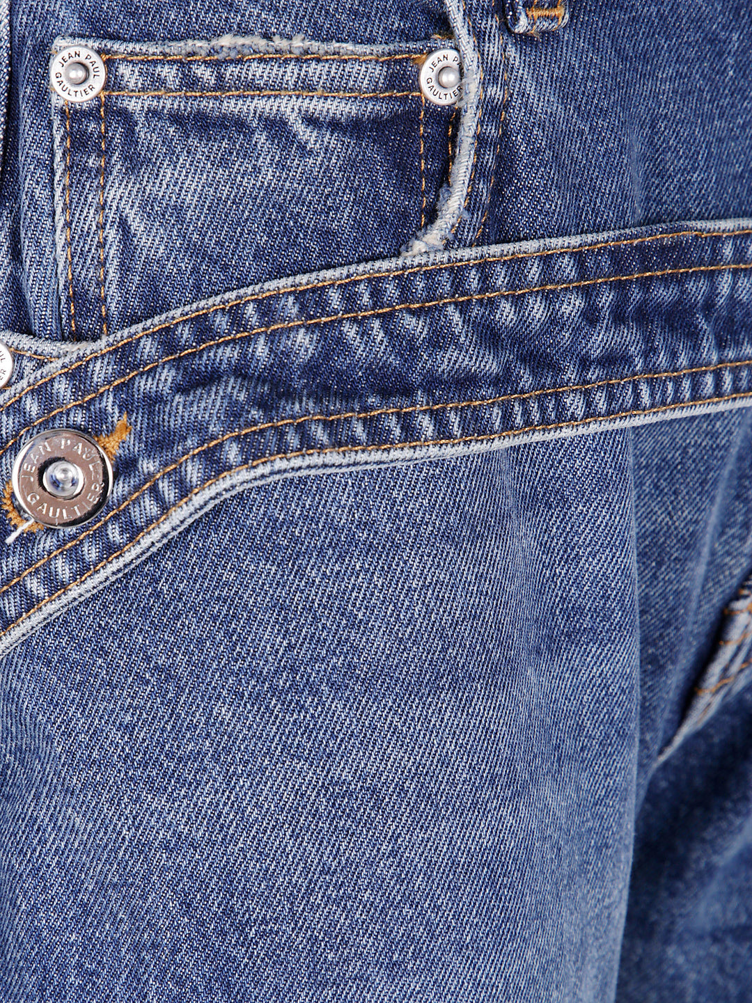 Close-up of blue denim fabric with stitching and buttons