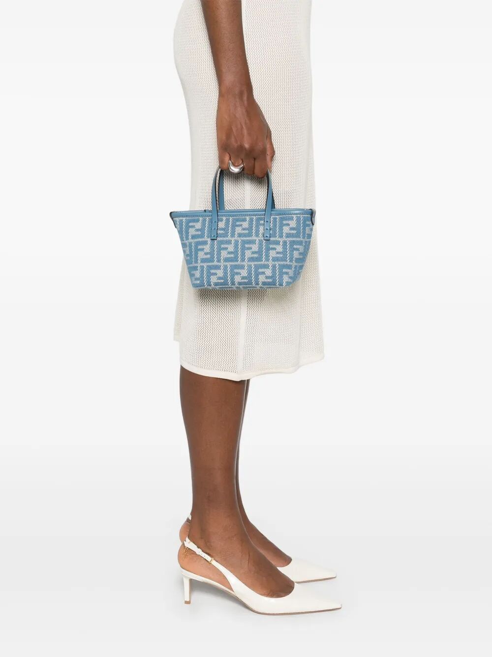 Person holding a blue patterned handbag on a white background