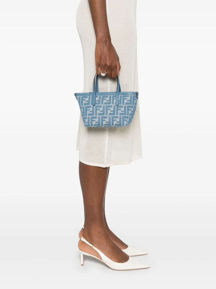 Person holding a blue patterned handbag on a white background