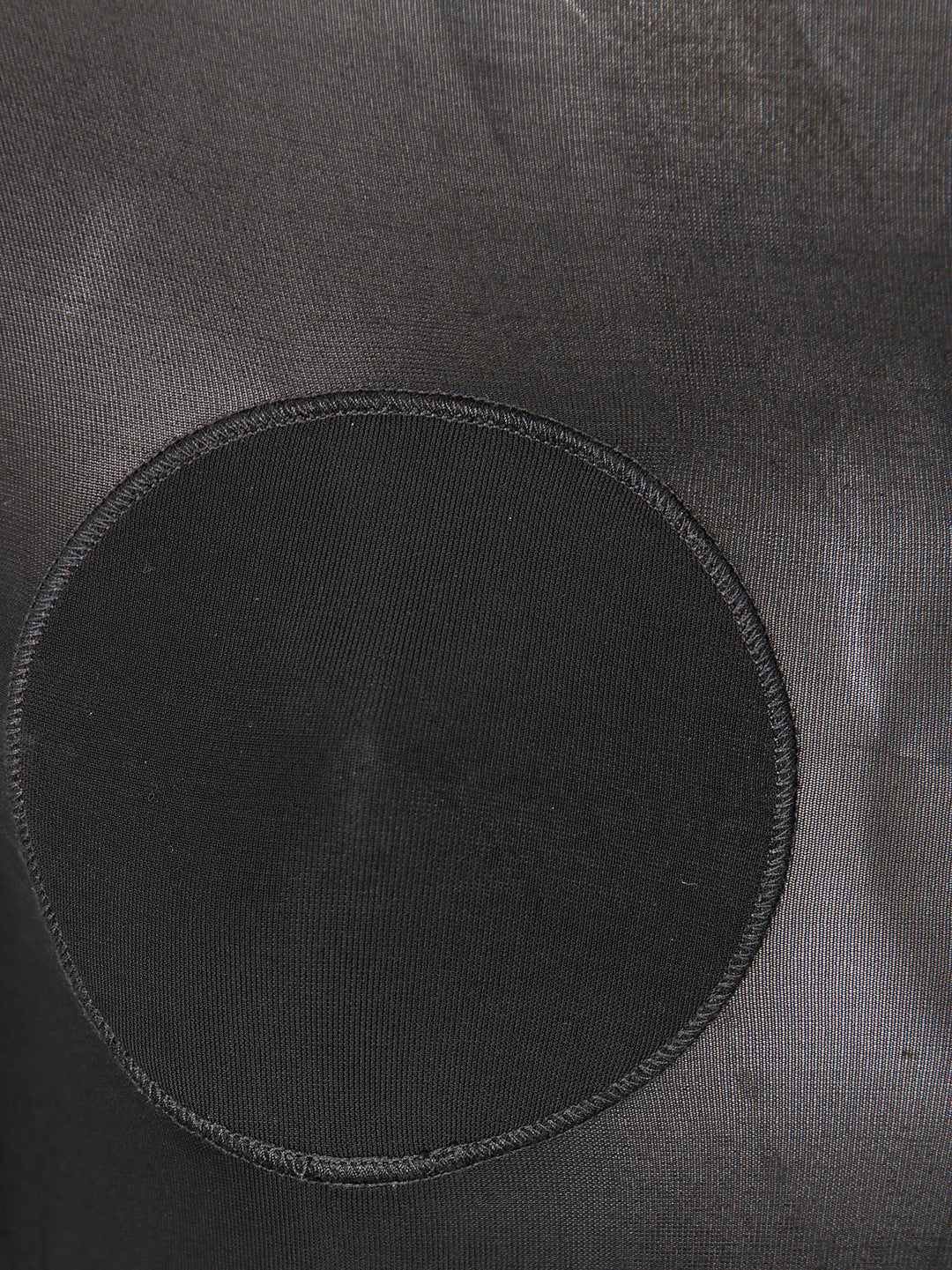 Black circular patch on a textured gray surface