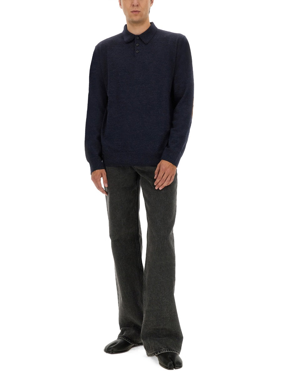 Man wearing a navy sweater and gray pants on a white background