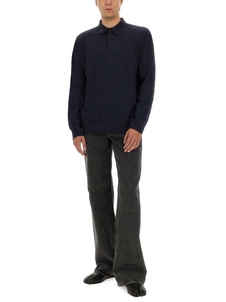 Man wearing a navy sweater and gray pants on a white background