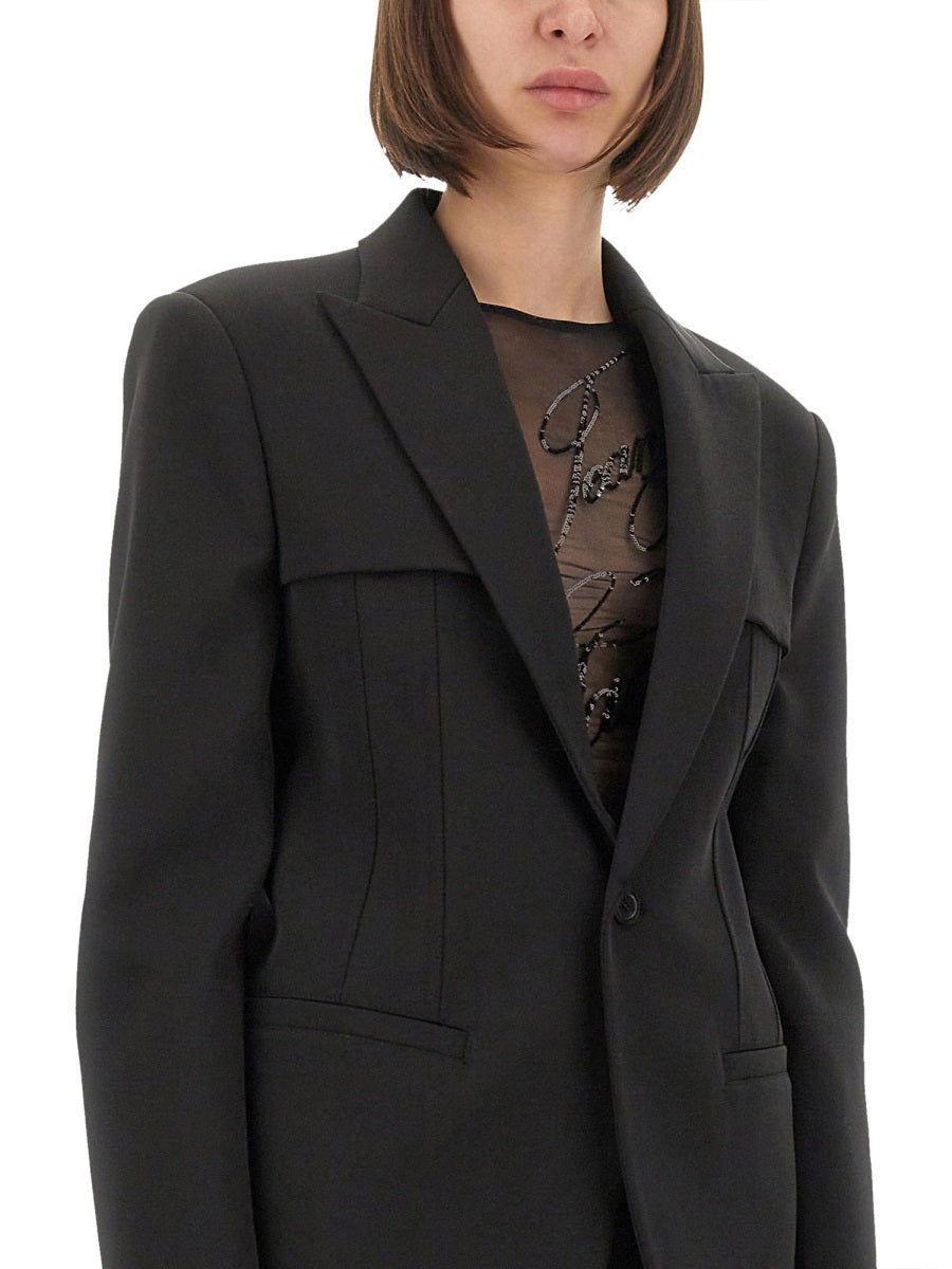 Person wearing a black blazer over a patterned top on a white background