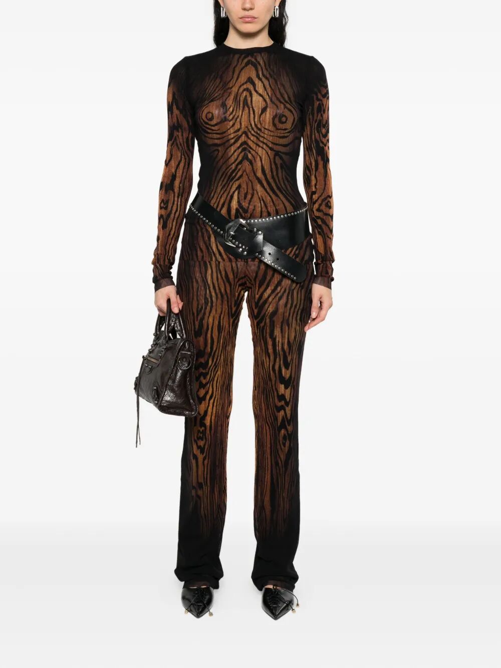Person wearing a black and brown patterned outfit with a belt and handbag on a white background