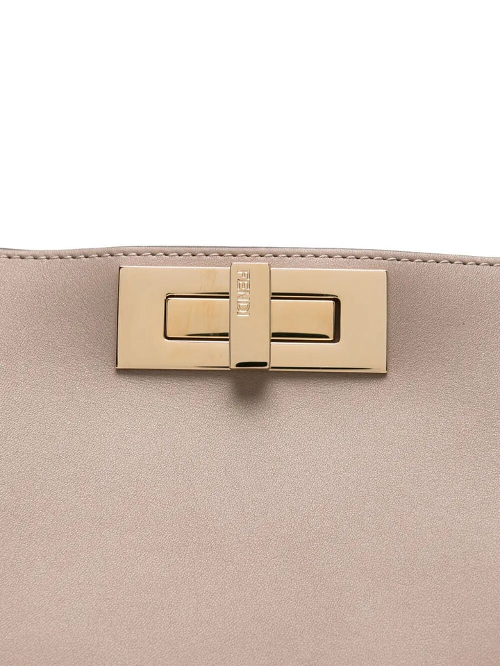 Close-up of a beige handbag with a gold clasp on a white background