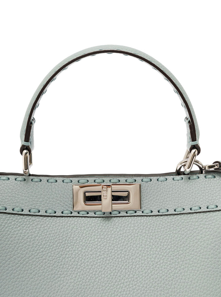 Close-up of a light blue handbag with a silver handle and clasp on a white background