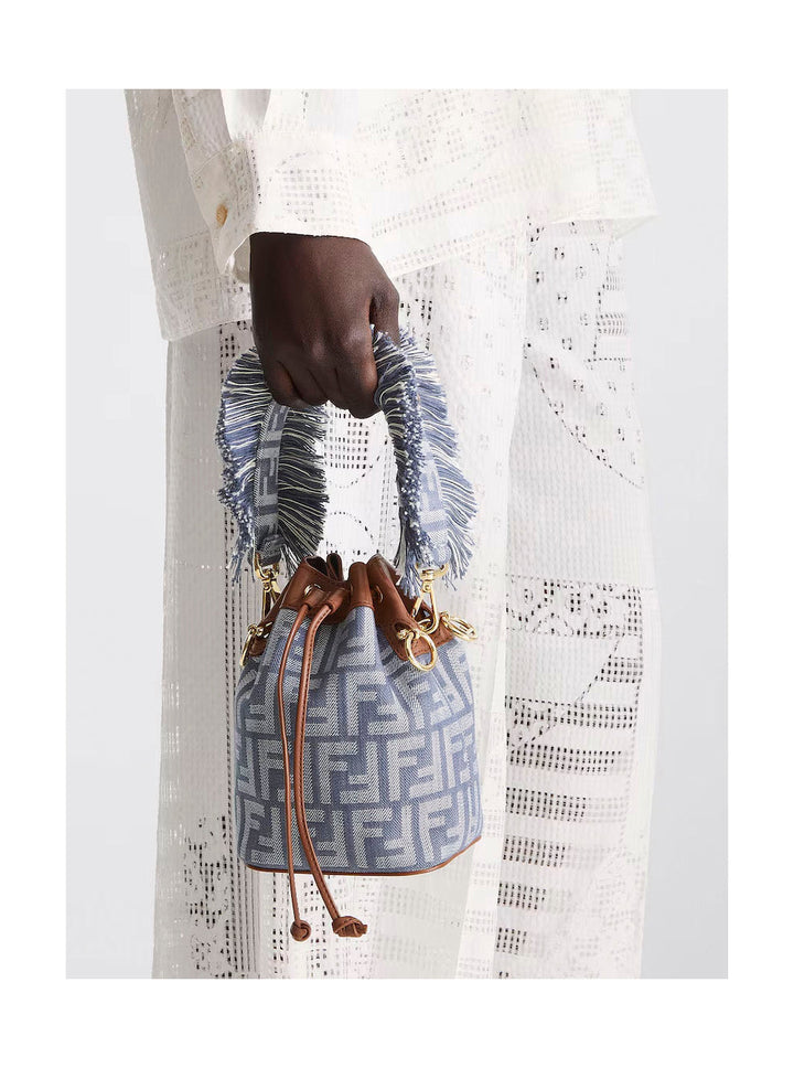 Hand holding a blue patterned handbag with a brand logo against a white background