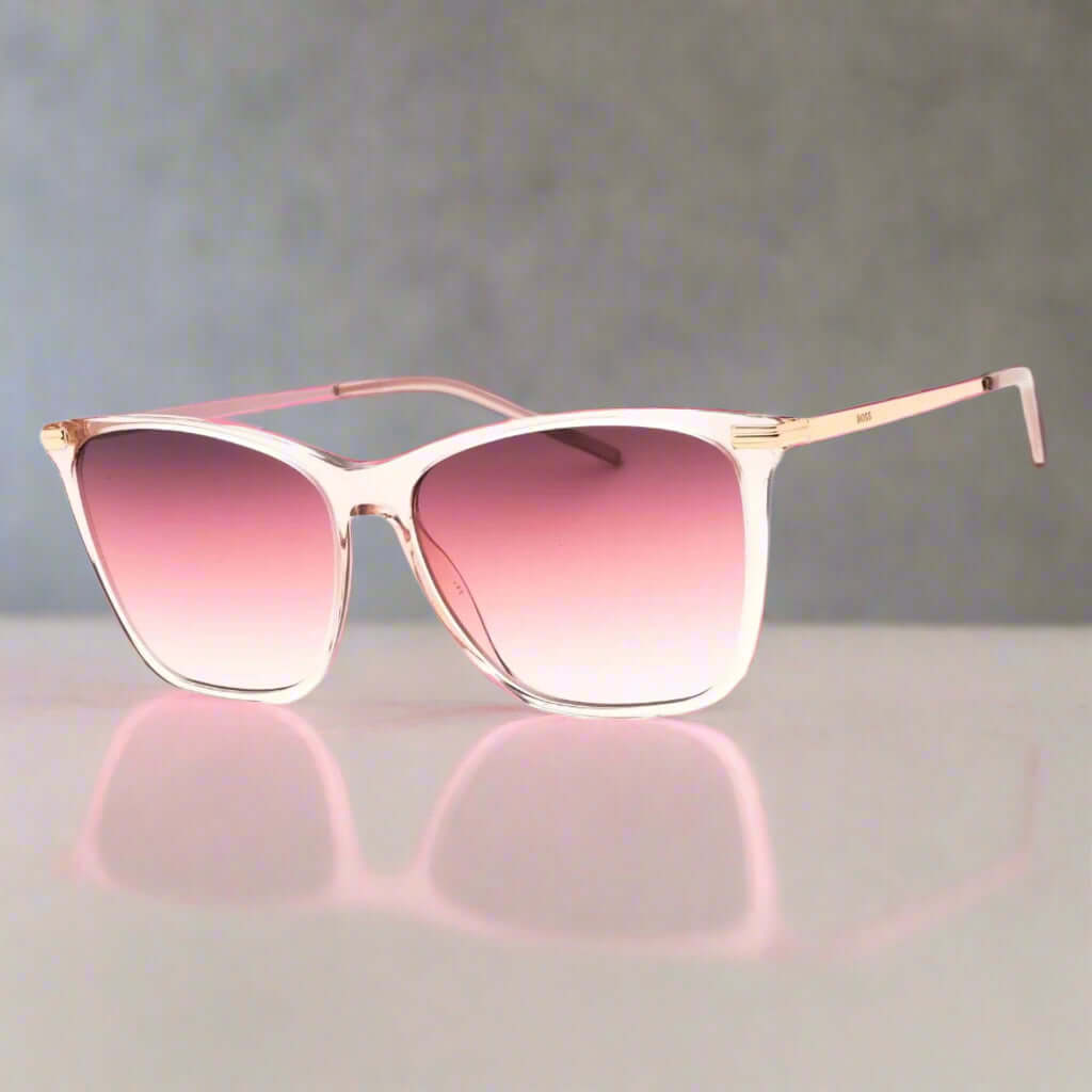 Sunglasses with pink gradient lenses and gold frame on a white background