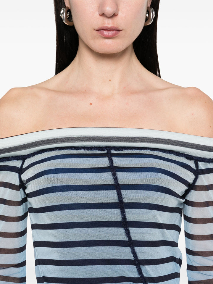 Close-up of a person wearing a blue and white striped off-shoulder top.