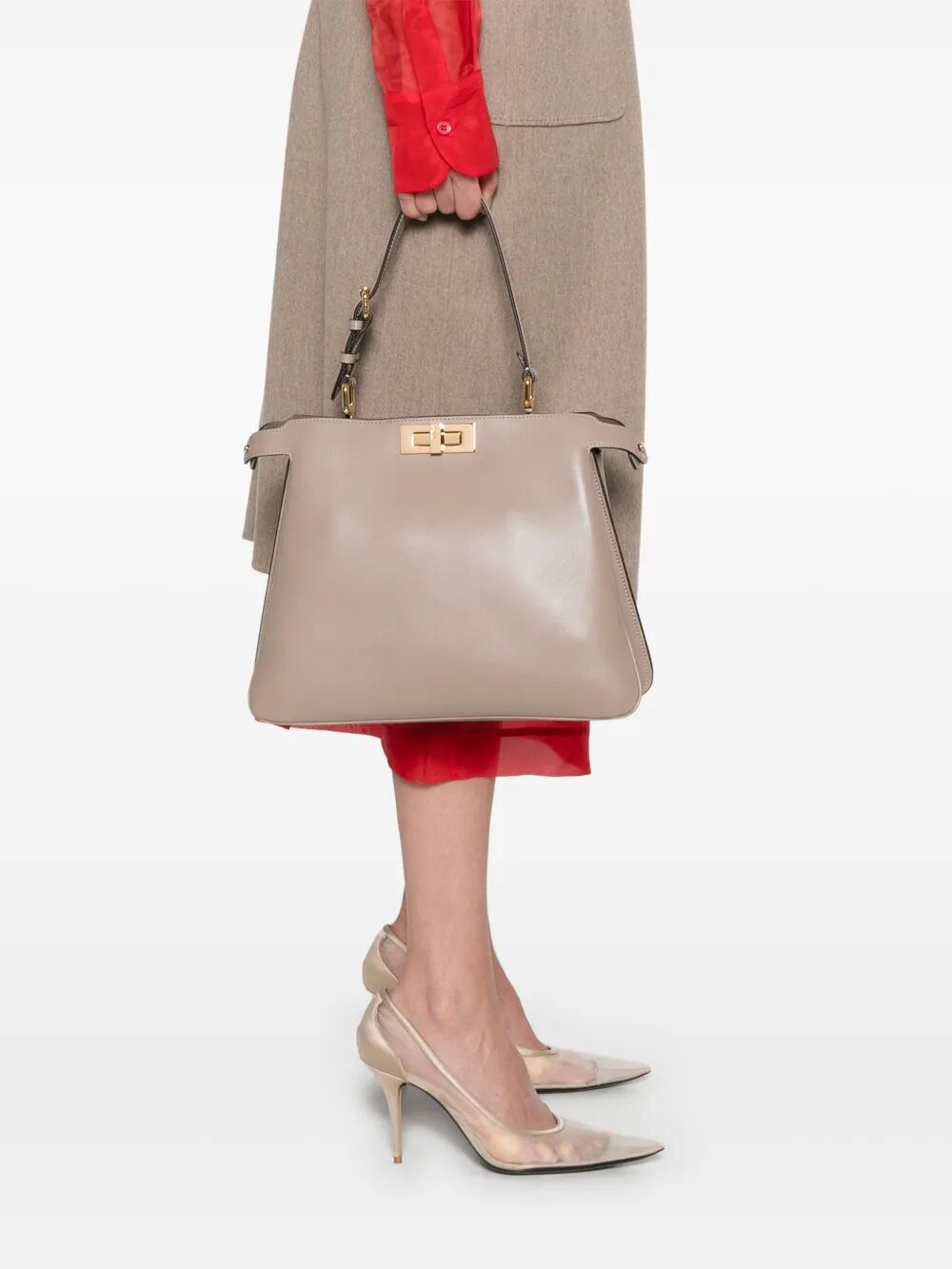 Person holding a beige handbag with a neutral background