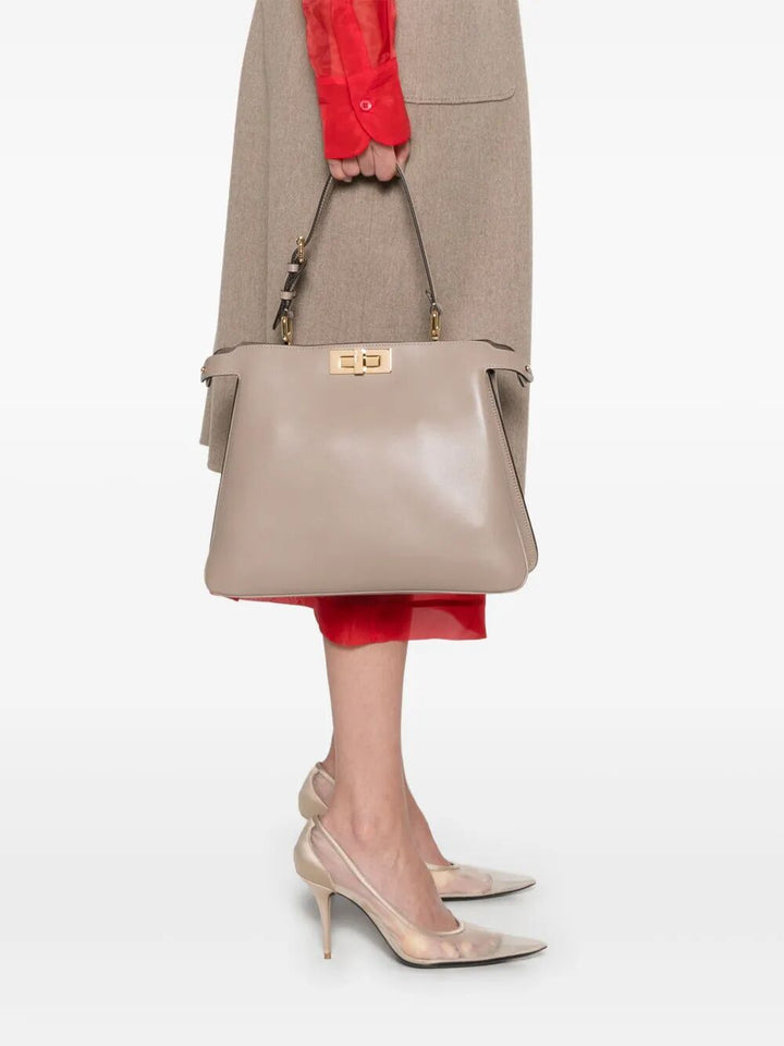 Person holding a beige handbag with a neutral background