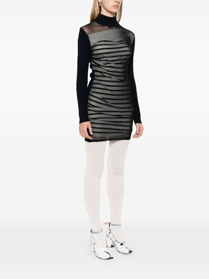 Person wearing a black and gray dress with white tights on a white background