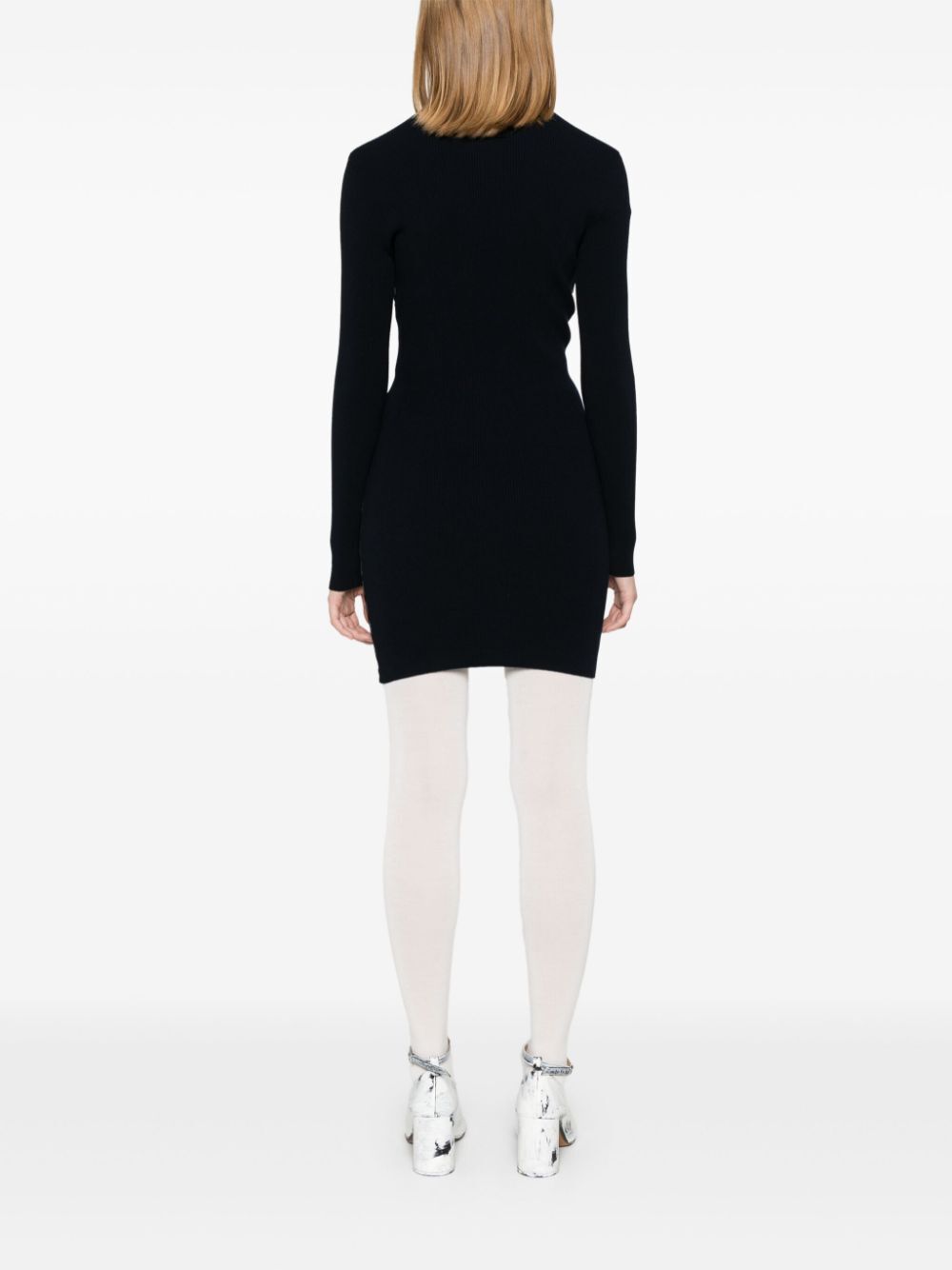 Person wearing a black dress and white tights on a white background