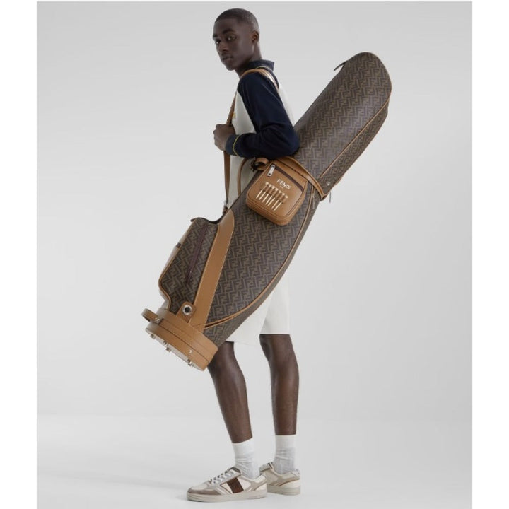 Man holding a large brown and tan golf bag against a white background