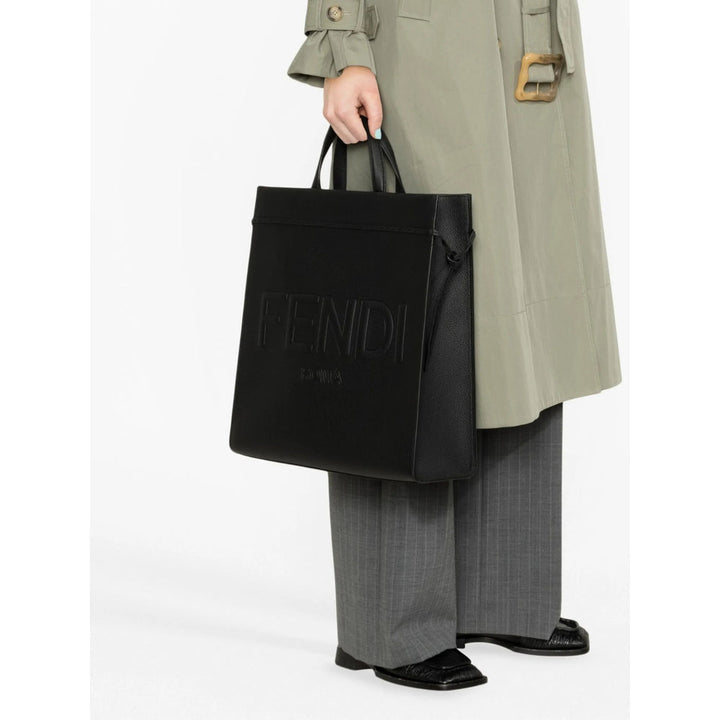Person holding a black Fendi bag with a white background