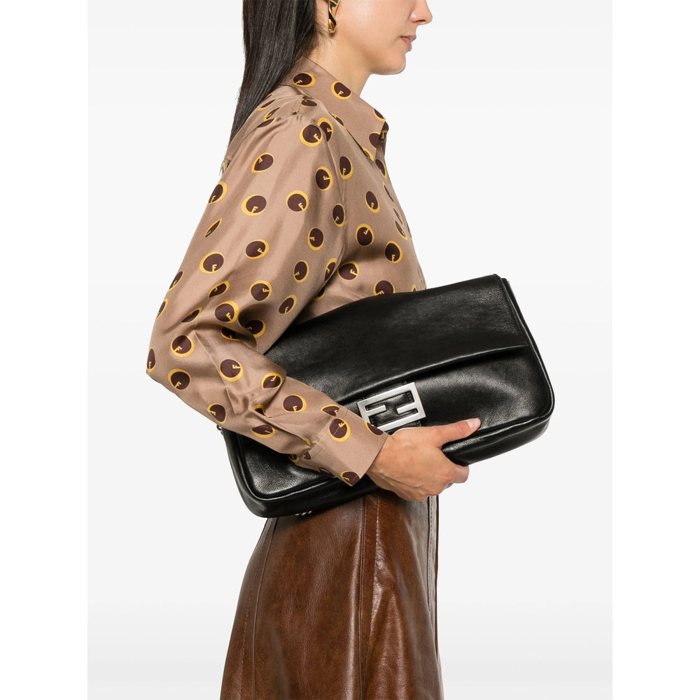 Person holding a black clutch bag with a plain background