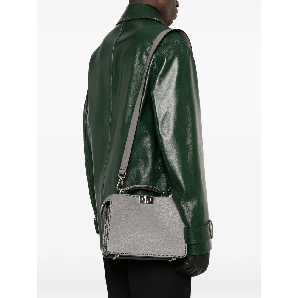 Person wearing a green leather jacket with a silver handbag on a white background