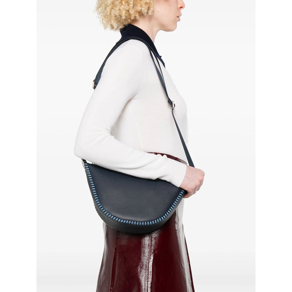 Person wearing a dark gray crossbody bag with a white background