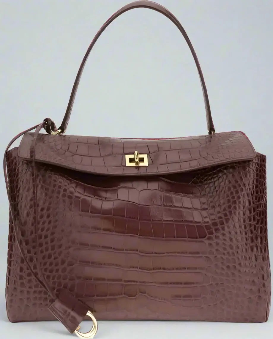 Brown crocodile-patterned handbag with a gold clasp on a white background