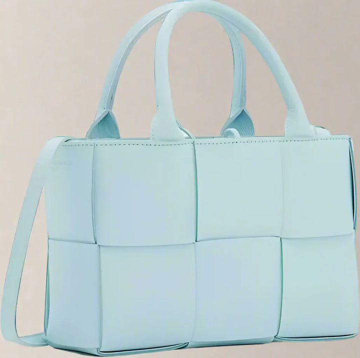 Light blue quilted handbag with a shoulder strap on a white background