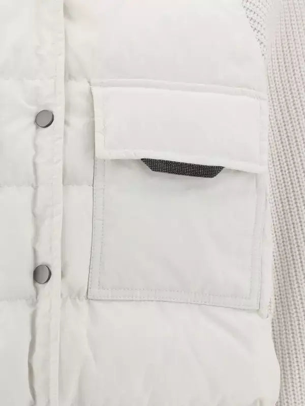 Close-up of a white denim jacket with a pocket and buttons.