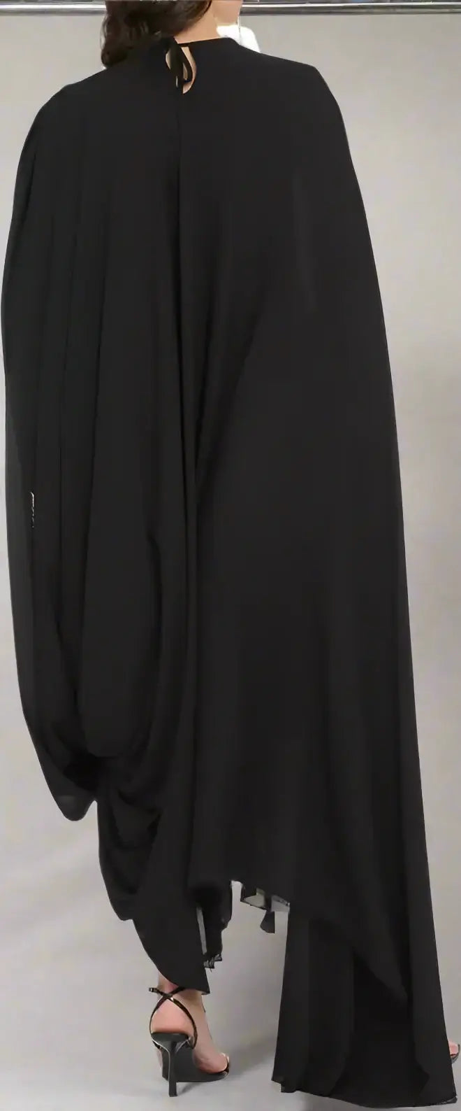 Black draped garment worn by a person on a white background