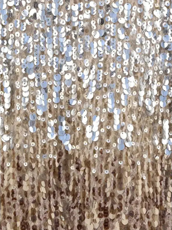 Close-up of a textured fabric with sequins and beads in neutral colors.