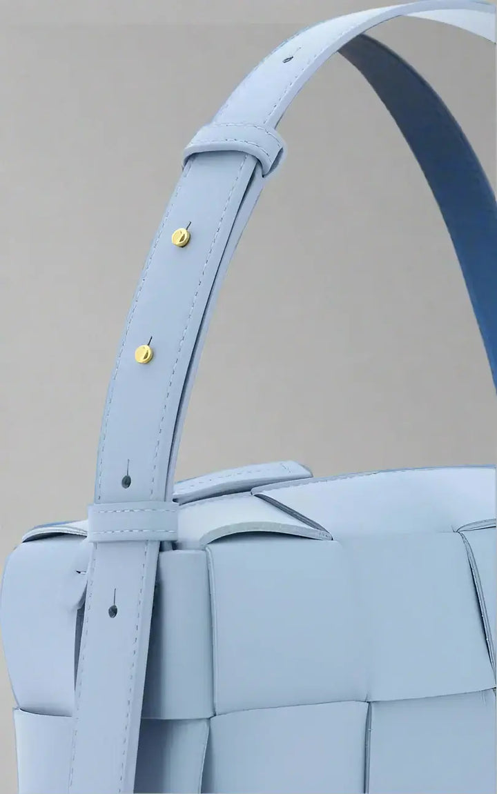 Light blue woven handbag with a strap on a white background