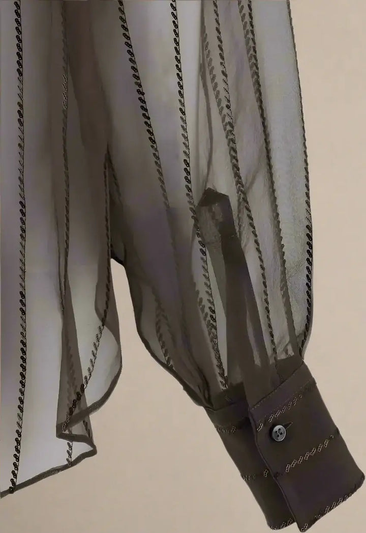 Sheer brown blouse with button details on a white background