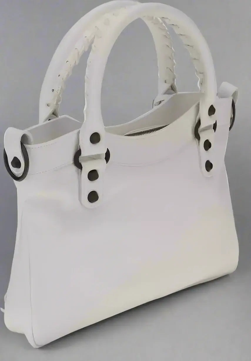 White handbag with black button details on a white background