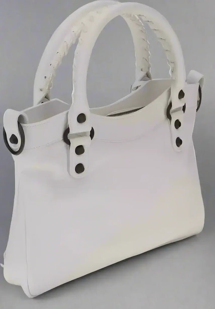 White handbag with black button details on a white background