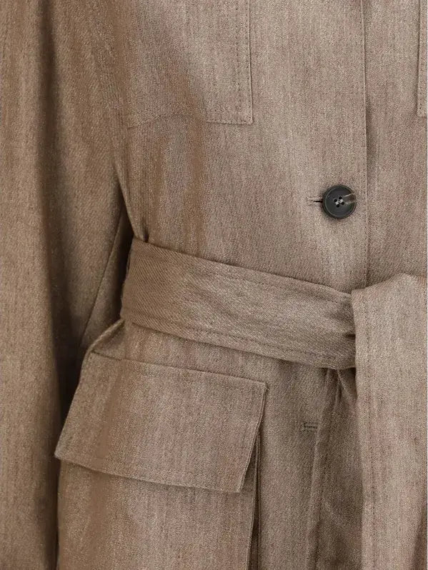 Close-up of a beige trench coat with a button and belt detail.