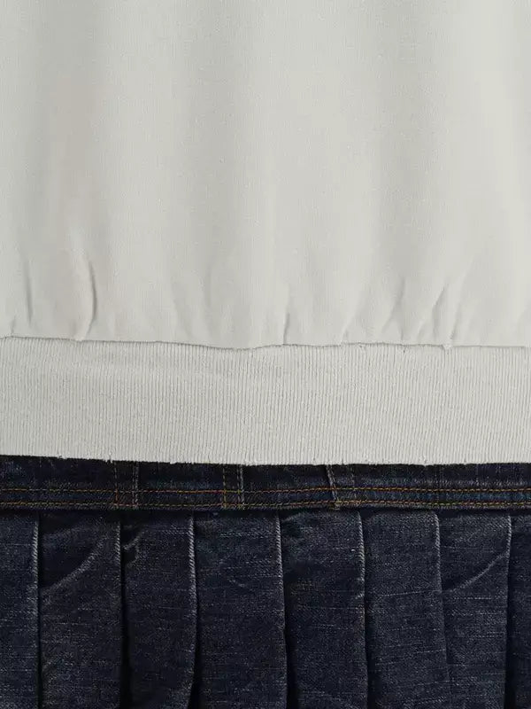 Close-up of a white shirt and blue jeans with a visible seam.