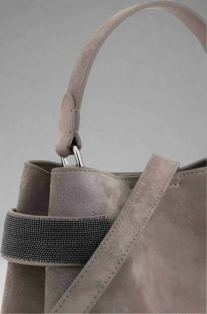 Close-up of a gray suede handbag with a strap on a white background