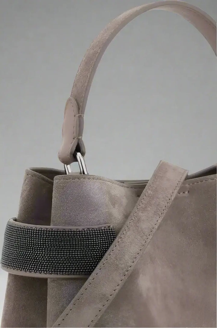 Close-up of a gray suede handbag with a strap on a white background
