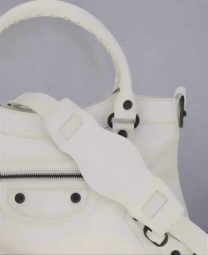 White leather handbag with a strap on a white background