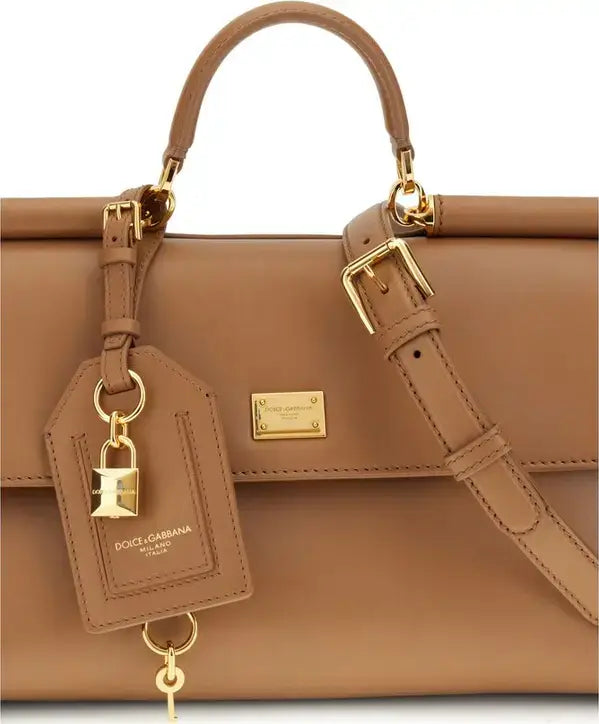 Brown handbag with gold accents and a visible brand tag on a white background