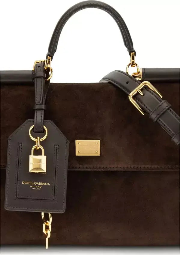 Brown handbag with gold accents and a matching keychain on a white background