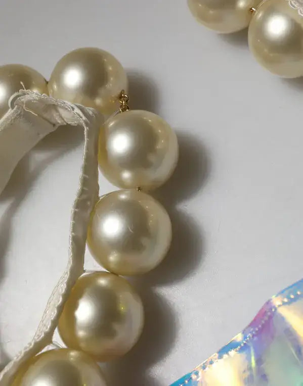 Pearl necklace on a white surface with a colorful object partially visible