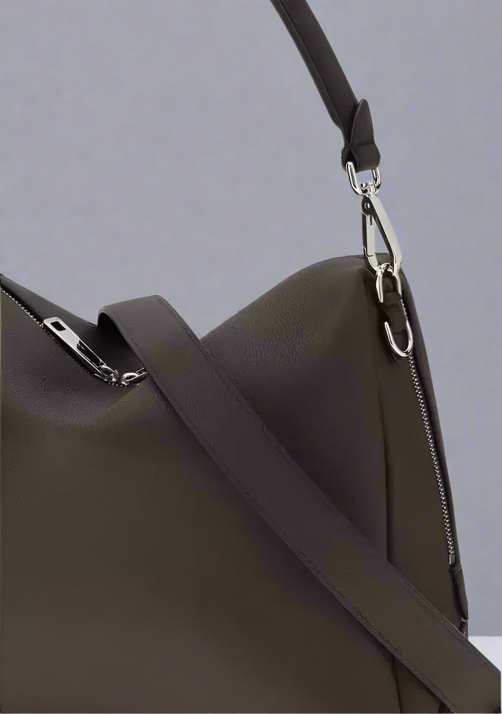 Close-up of a dark brown leather bag with a shoulder strap and silver zipper.