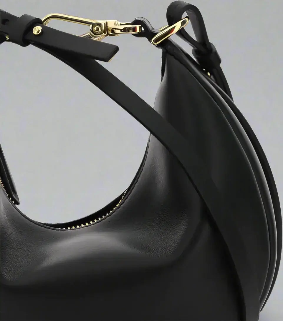 Black leather handbag with gold hardware on a white background