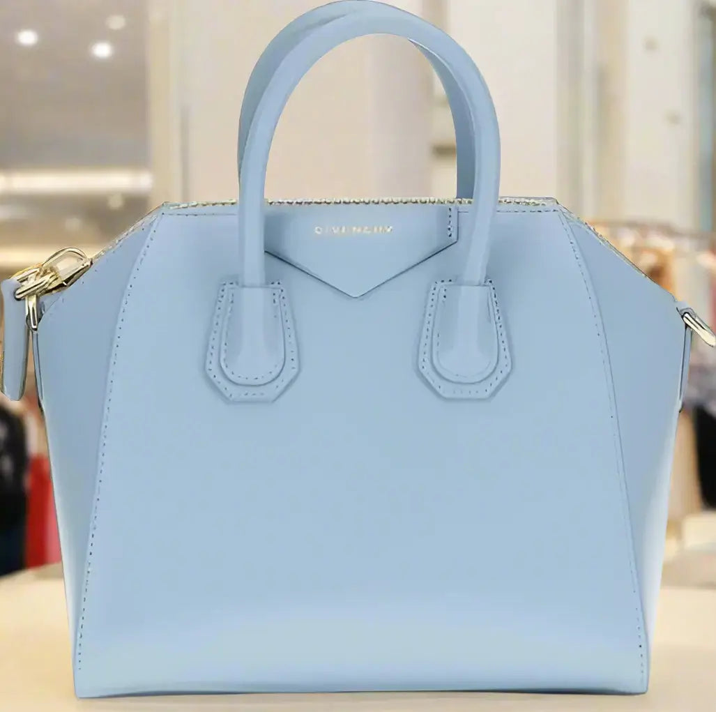 Light blue handbag with gold accents on a white background