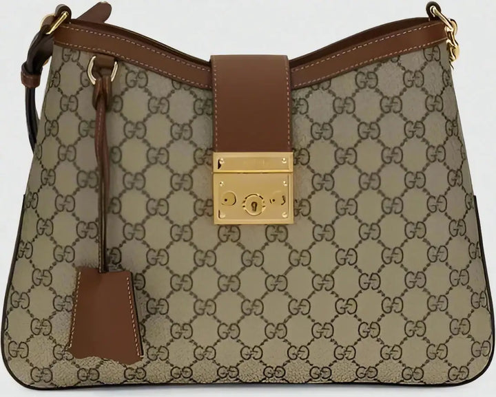 Designer handbag with brown and beige patterned fabric and gold lock detail.