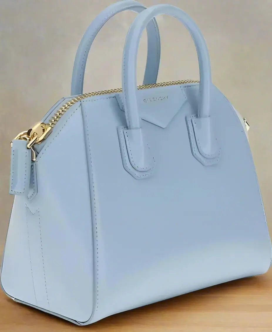 Light blue handbag with gold zipper on a white background