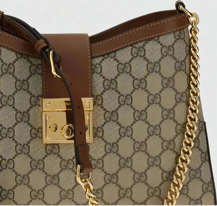 Designer handbag with gold chain and brown leather accents on a white background