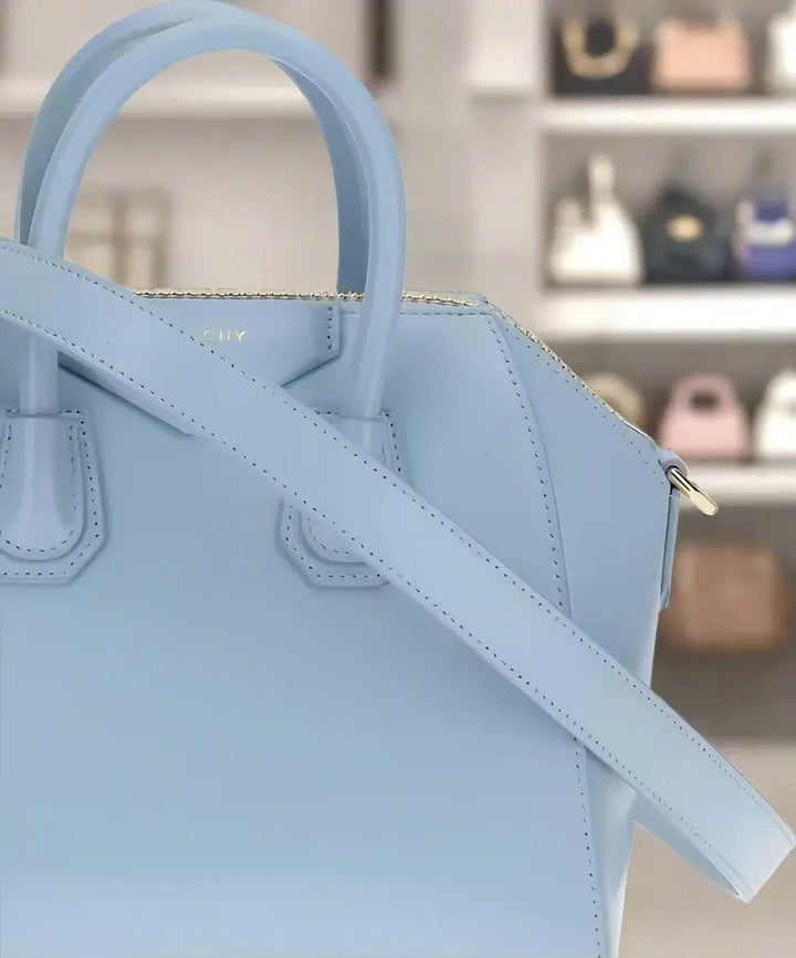 Light blue handbag with a gold zipper on a white background