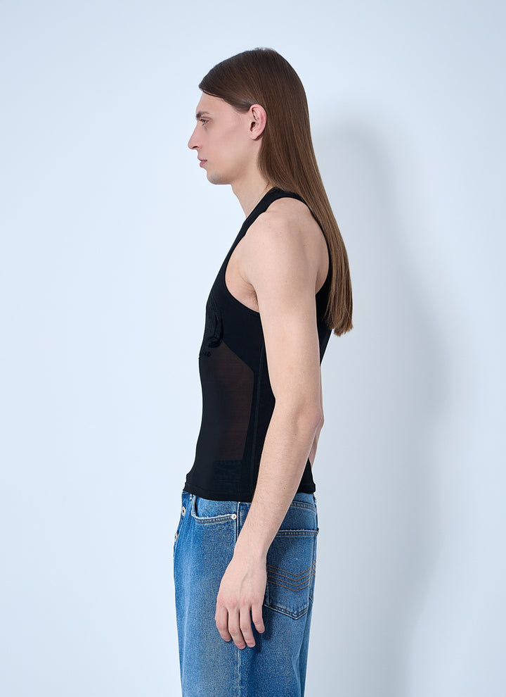 Woman wearing a black sleeveless top and blue jeans against a white background