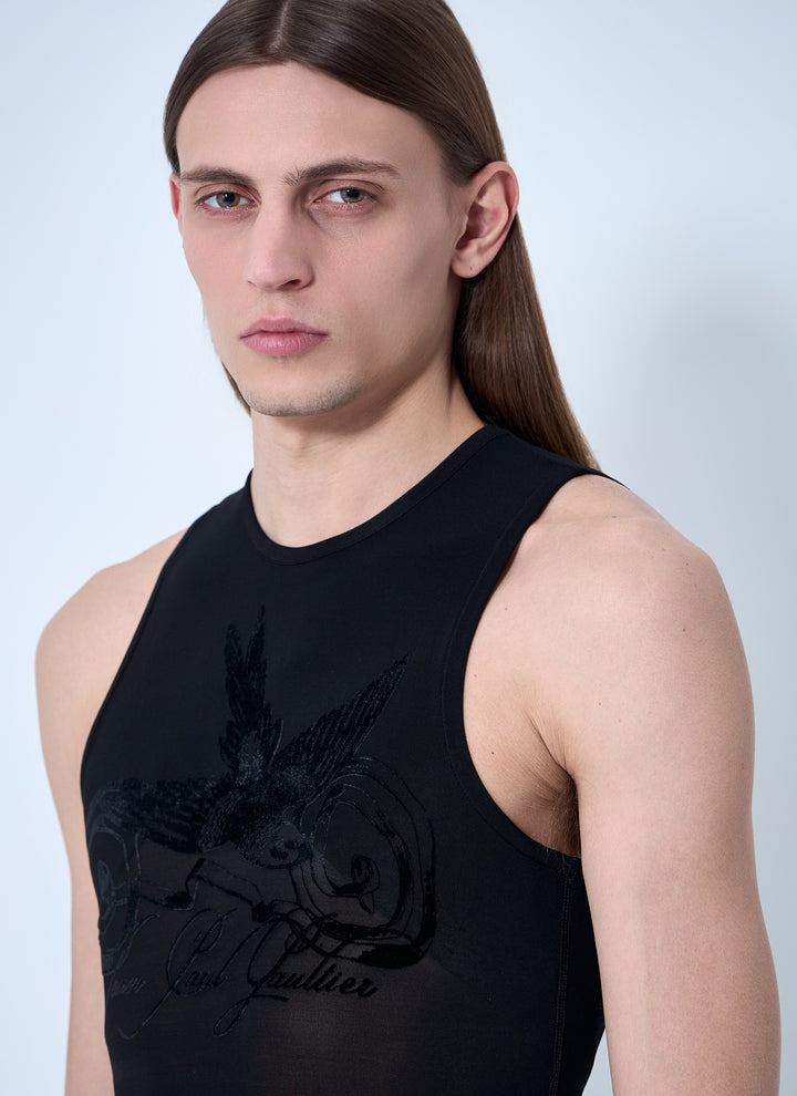Person wearing a black sleeveless shirt with a design on a light gray background