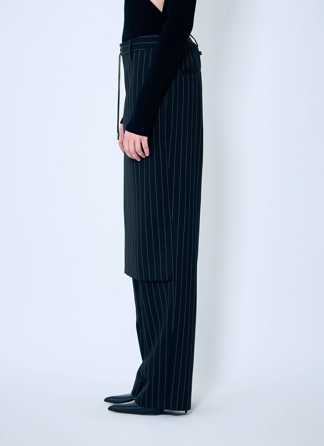 Person wearing black pinstripe pants on a white background