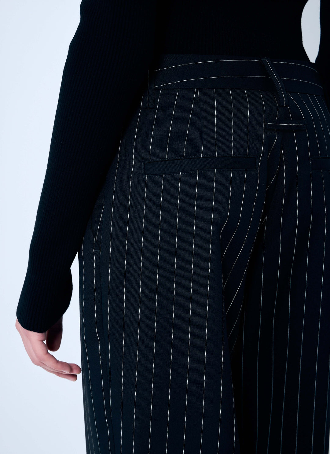 Black pinstripe pants worn by a person on a light gray background